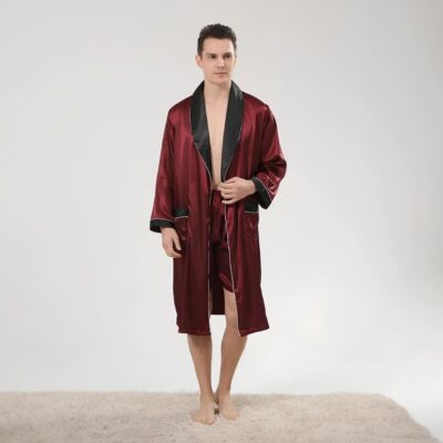 Peignoir bicolore en satin pour homme de couleur noir et bordeaux porté par un homme brun debout sur un tapis beige.