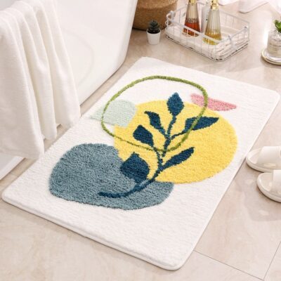 Tapis de salle de bain absorbant et épais, dans sa version jaune, au pied d'une baignoire, sur laquelle est déposée une serviette de bain.On aperçoit une paire de pantoufles à côté du tapis.