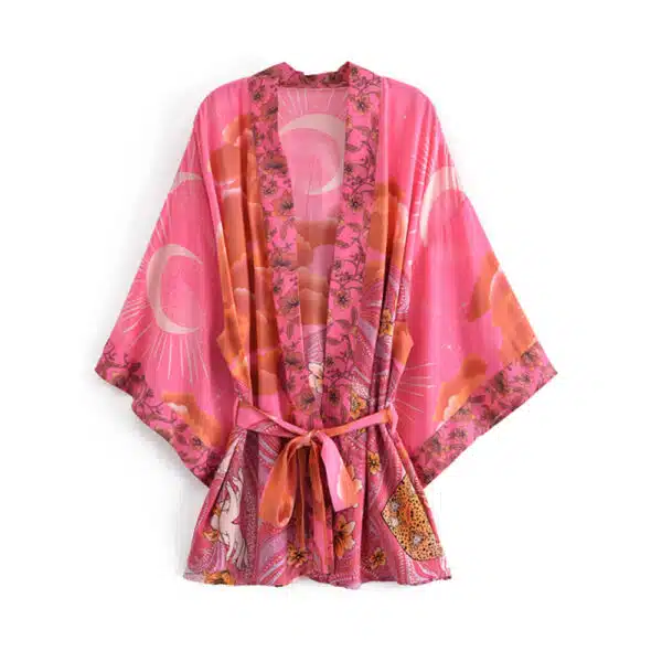 Sur fond blanc, on voit un peignoir style kimono rose imprimé de lunes et de fleurs. Les manches chauve-souris et la ceinture sont superbes.