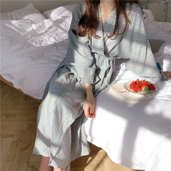 photo d'une femme portant un peignoir à carreaux vert assise sur un lit avec une assiette de fraise