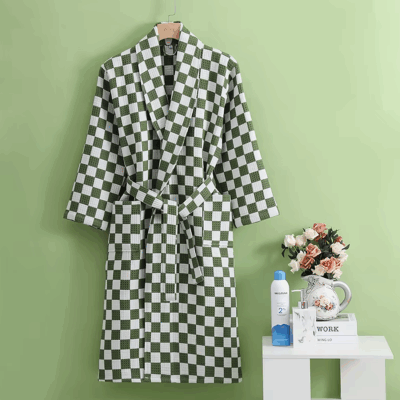 Photo d'un peignoir en nid d'abeille ) motif damier vert et blanc, sur fond vert avec une petite table avec des fleur à côté