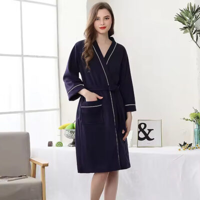 Photo d'une femme portant un peignoir en nid d'abeille bleu marine avec un liseret blanc, elle a une main dans la poche.